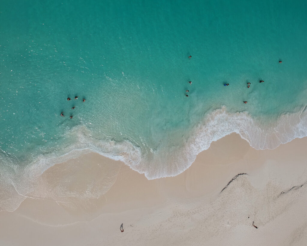 Aerial view of Aruba's coastline with turquoise shallows meeting white sand
